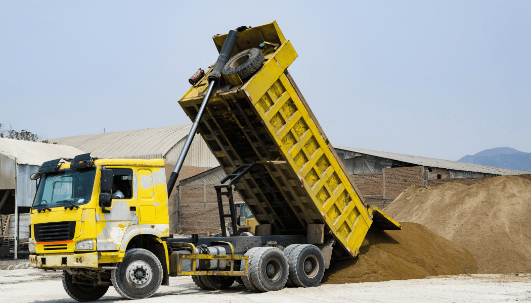 A dump truck dumping sand in a construction site